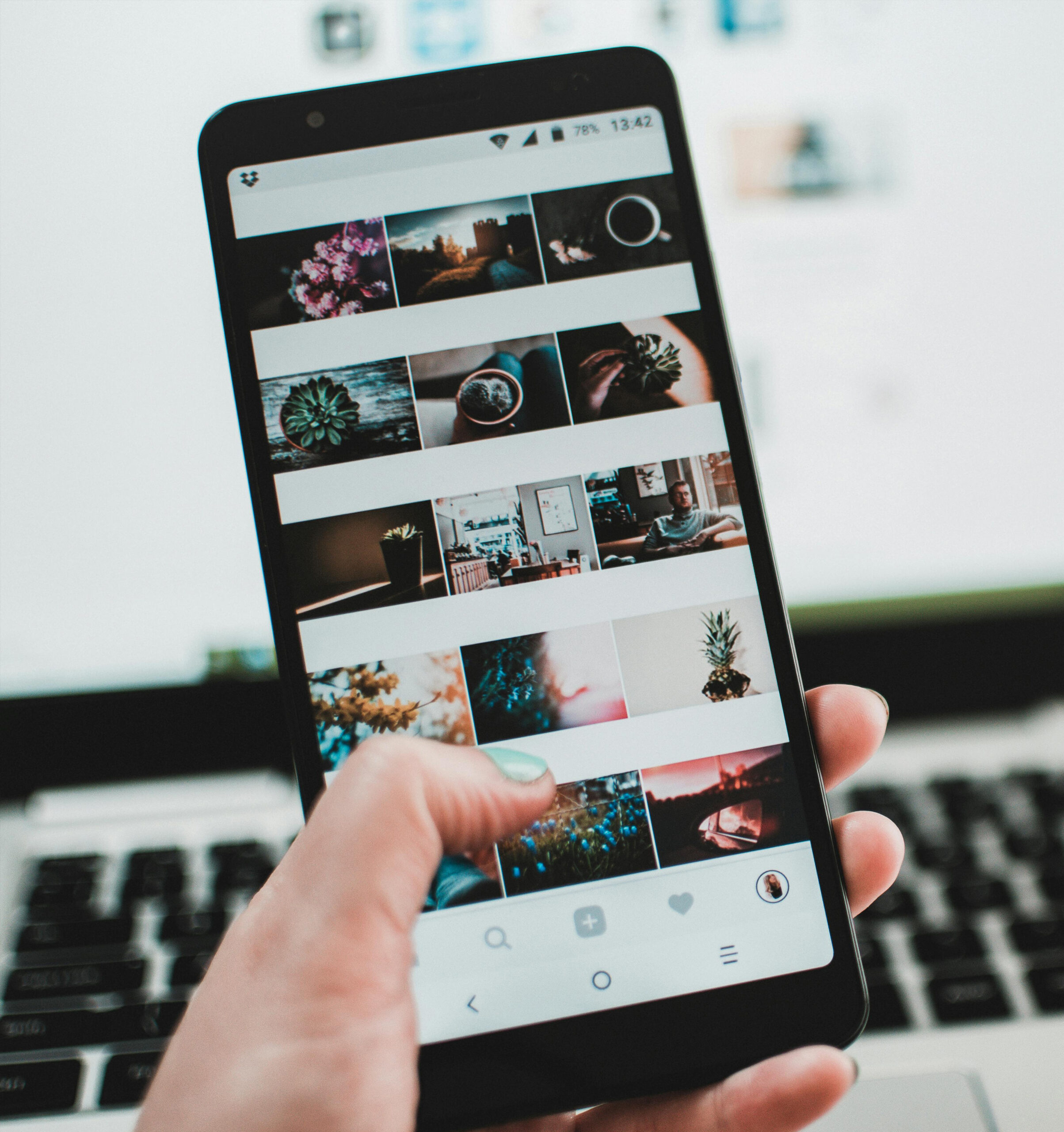Hand scrolling through a smartphone gallery filled with travel photos.