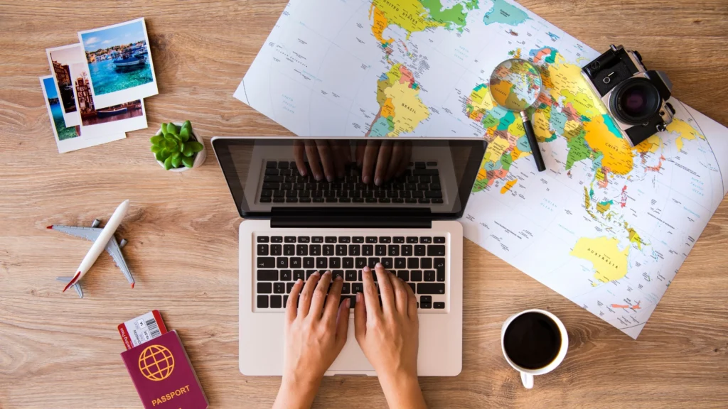 A laptop on a desk with travel maps, photos, and a passport, symbolizing how travel memories can inspire future journeys and new chapters.